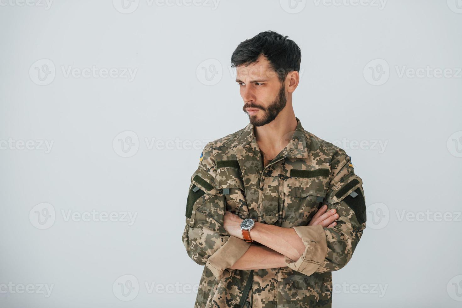 Soldier in uniform is standing indoors against white wall photo