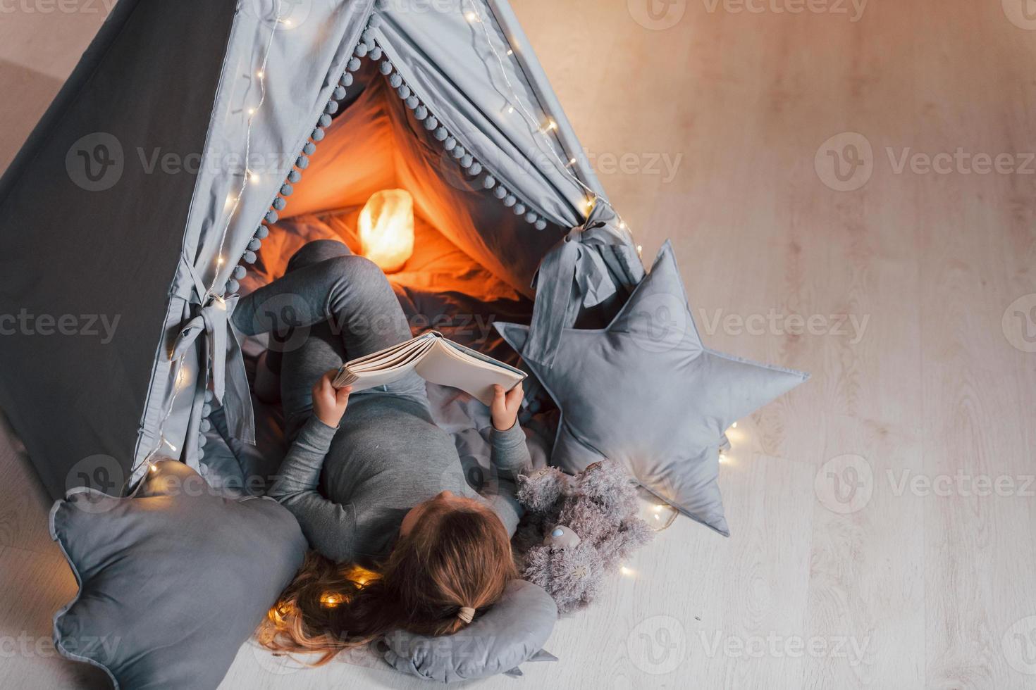 Interesting book. Cute little girl playing in the tent that is in the domestic room photo
