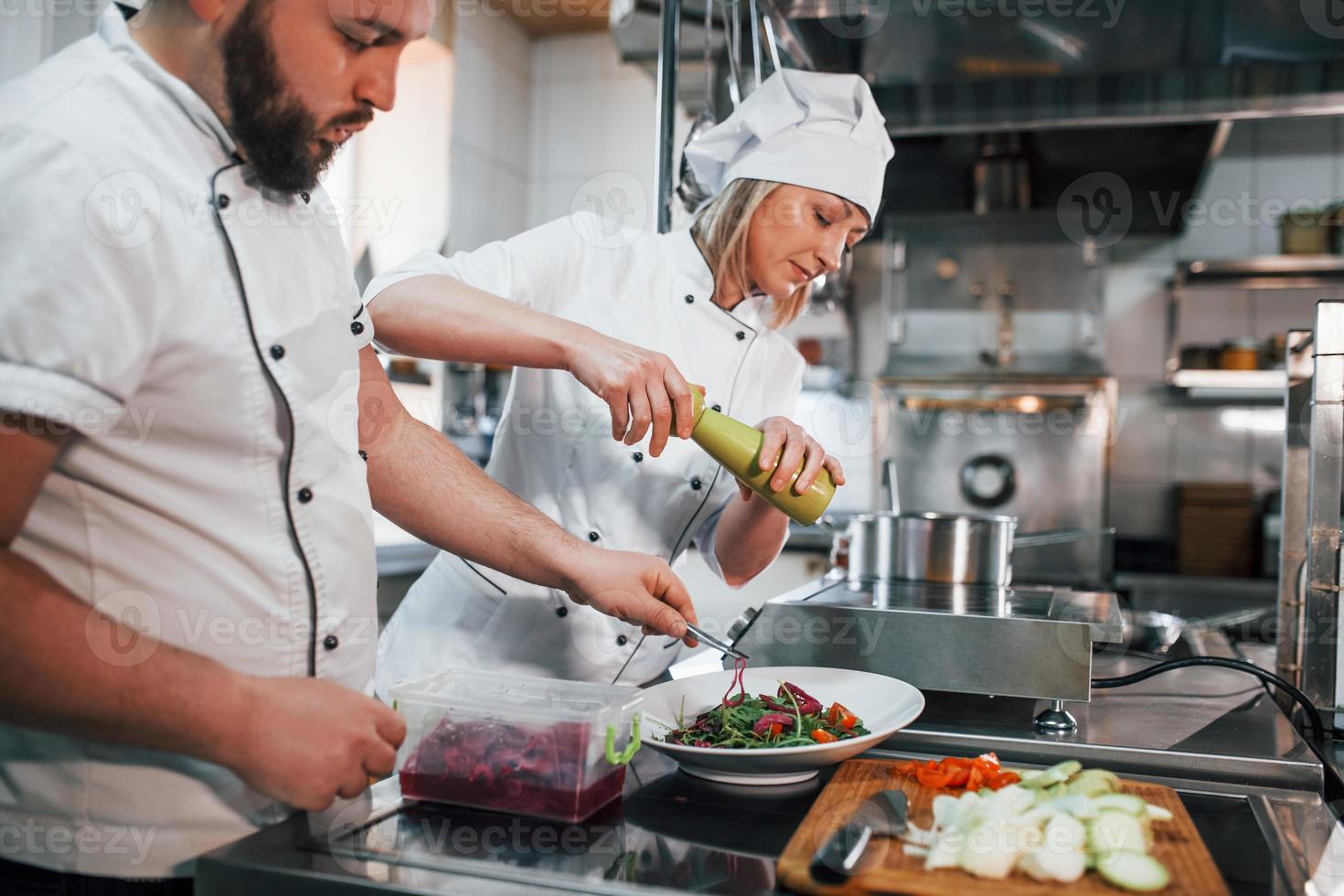 Three people. Making vegan salad. Professional chef preparing food in the kitchen photo