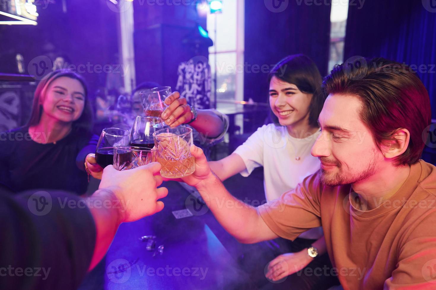 Sitting by the table together. Group of friends having fun in the night club photo