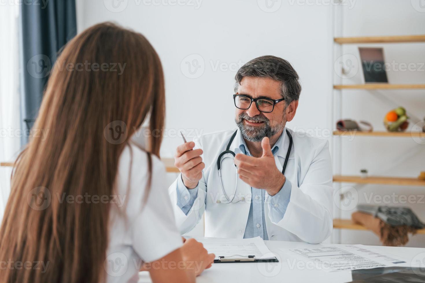 Male doctor giving consultation to the woman. Professional medical worker in white coat is in the office photo