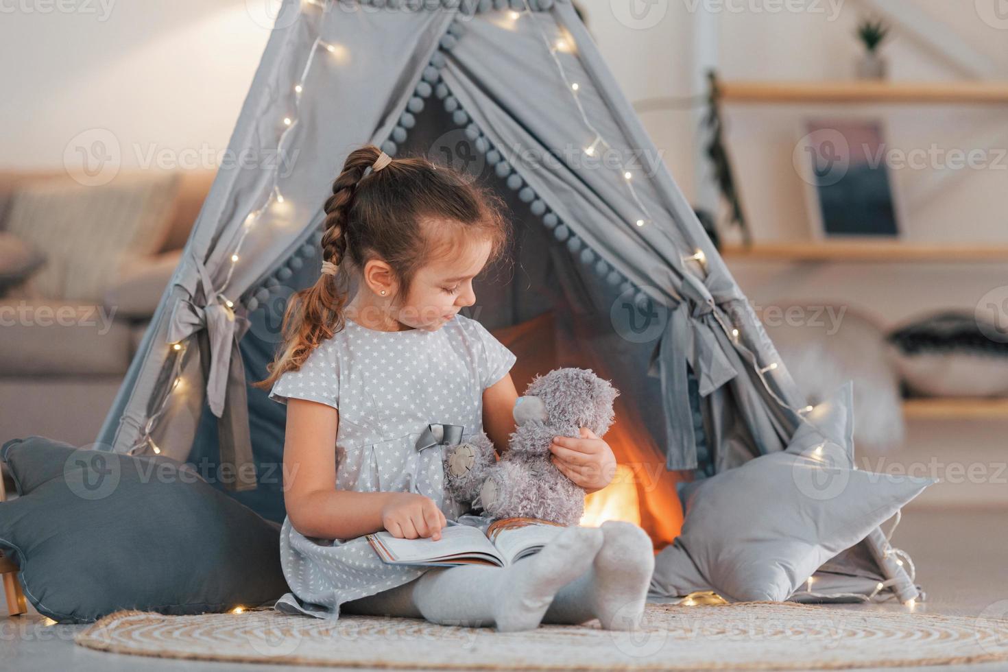 With toy. Cute little girl playing in the tent that is in the domestic room photo