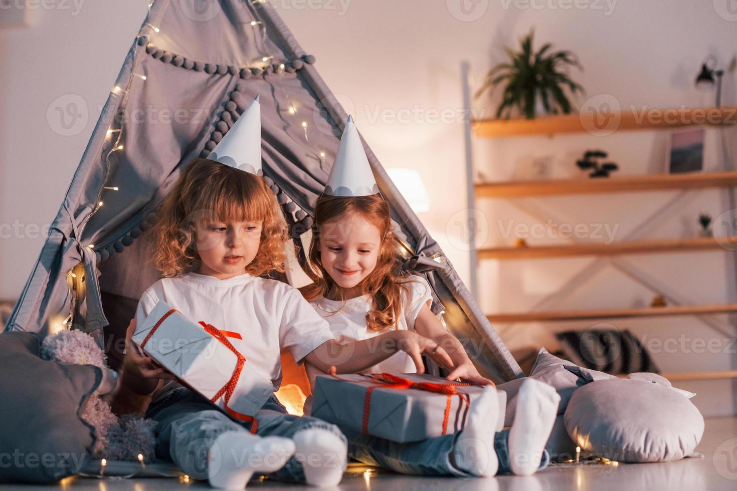 sorpresa de vacaciones. con cajas de regalo. dos niñas pequeñas están juntas en la tienda en la habitación doméstica foto