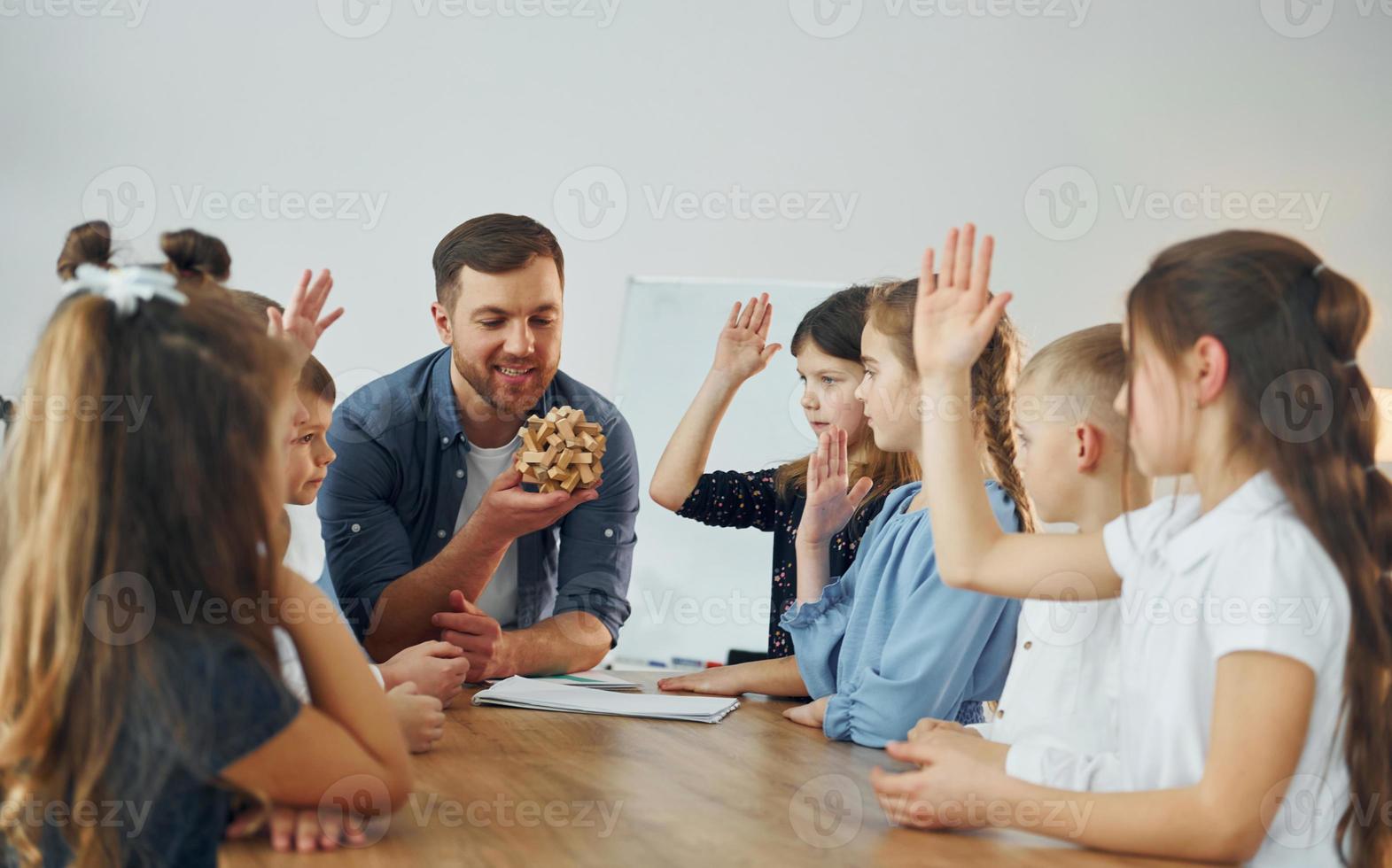 With puzzle. Group of children students in class at school with teacher photo