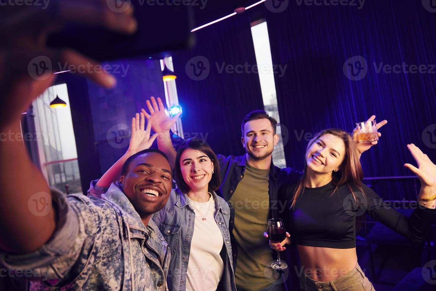 Making selfie. Group of friends having fun in the night club together photo