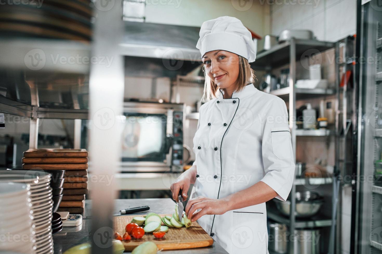 mujer haciendo ensalada. chef profesional preparando comida en la cocina foto