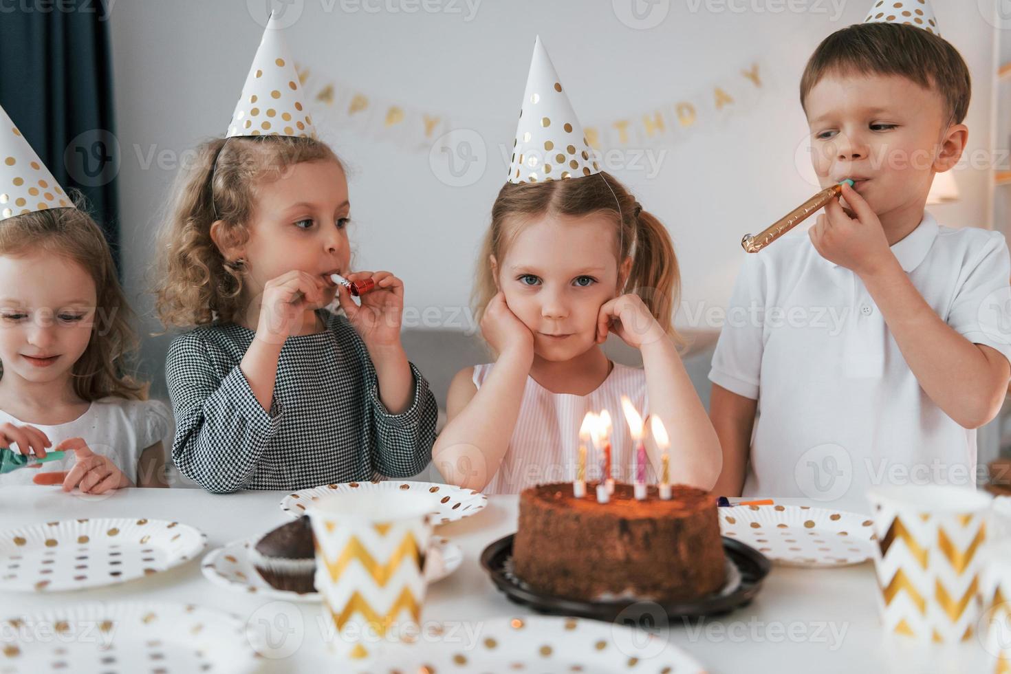 Sweet cake is on the table. Celebrating brithday. Group of children is together at home at daytime photo