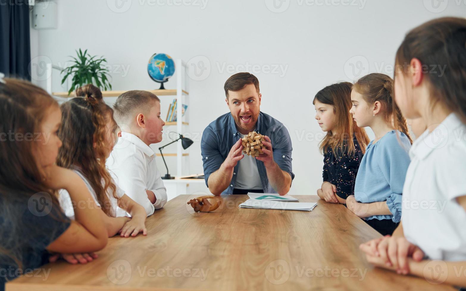 Exploring puzzle toy. Group of children students in class at school with teacher photo