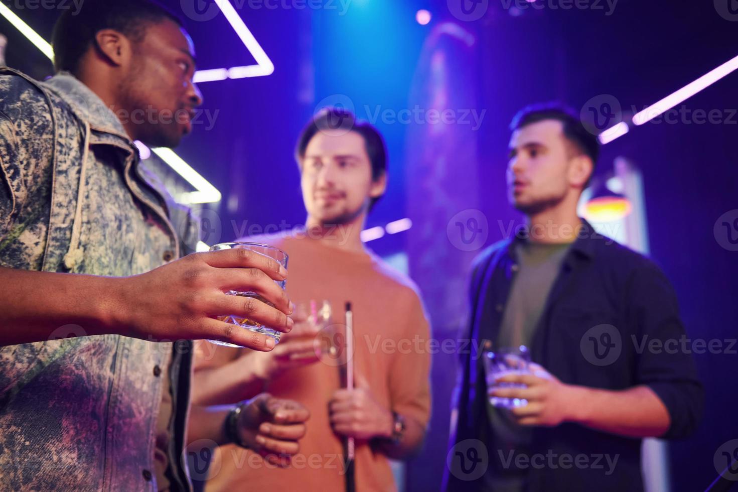 interior de iluminación azul. grupo de amigos divirtiéndose juntos en la discoteca foto