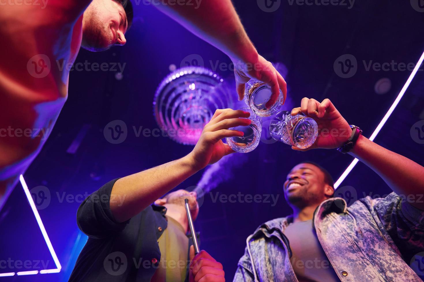 View from below. Group of friends having fun in the night club together photo