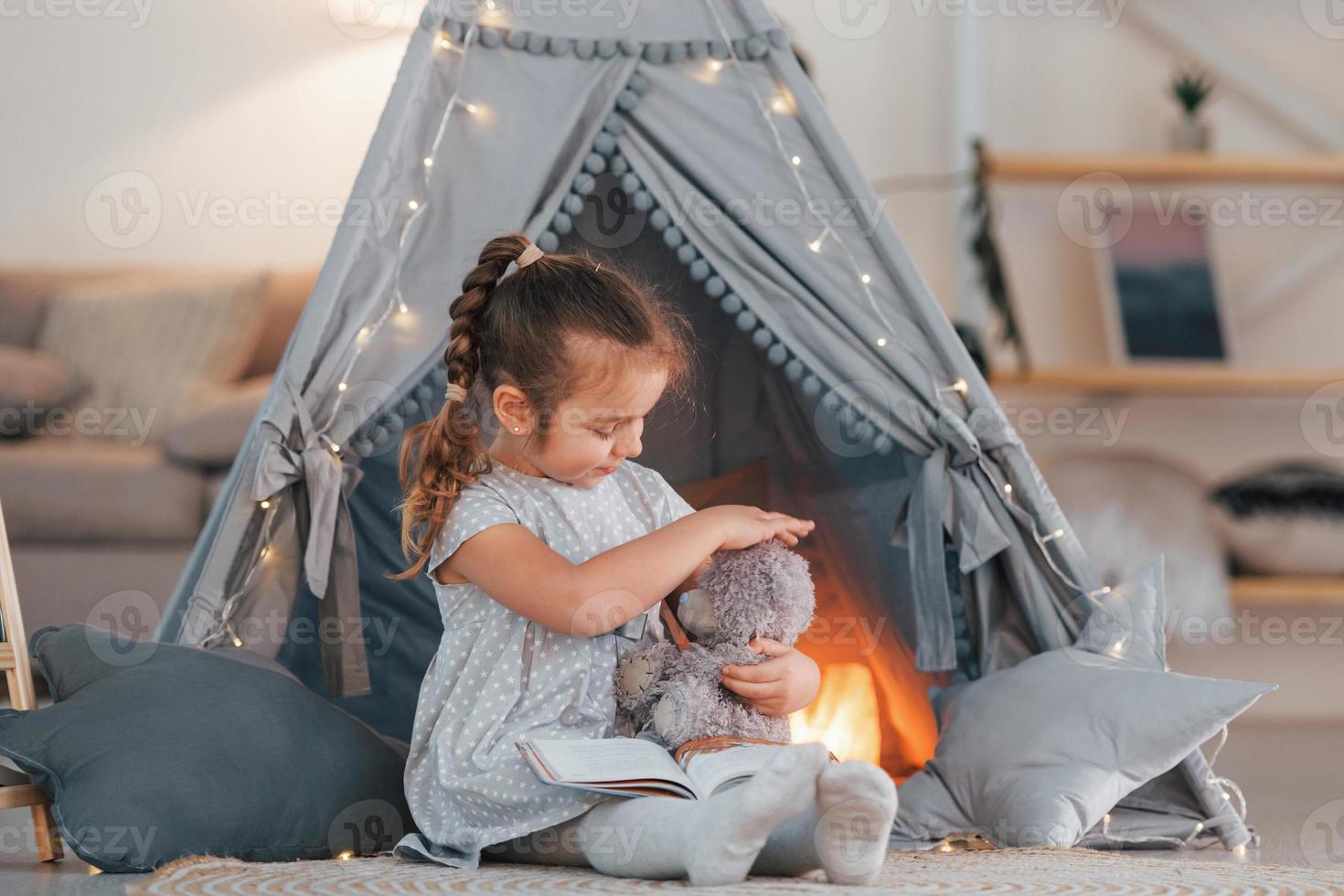 With toy. Cute little girl playing in the tent that is in the domestic room photo