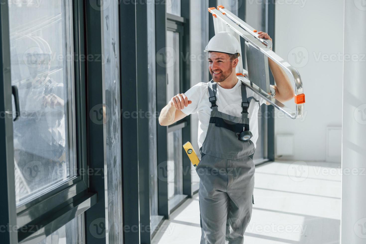 Holding ladder. Repairman is working indoors in the modern room photo