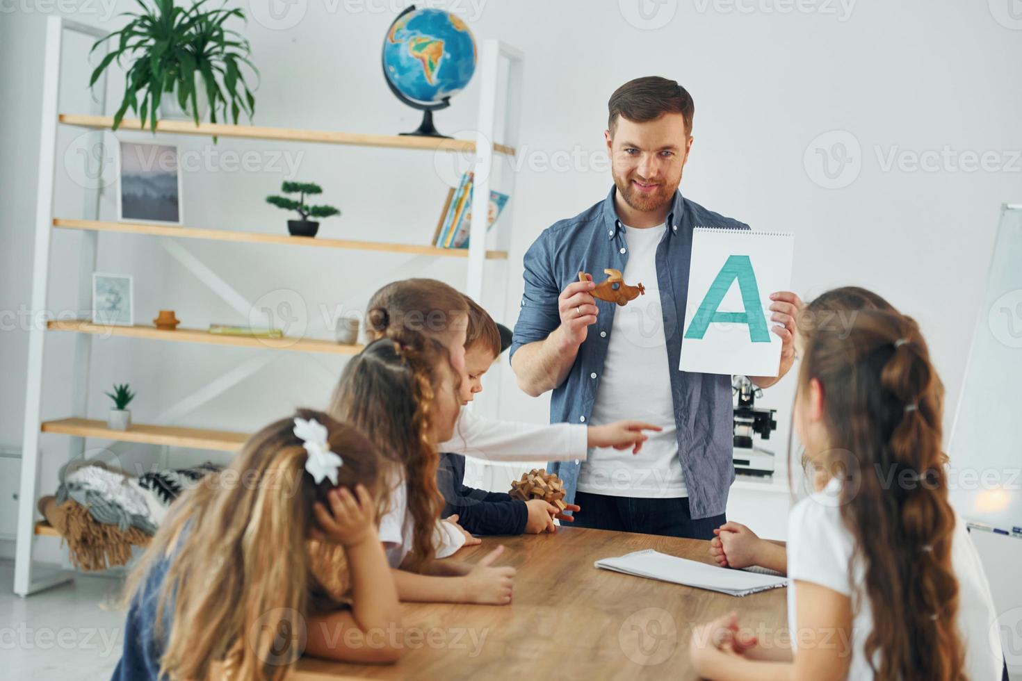 aprende una nueva letra. grupo de niños estudiantes en clase en la escuela con el maestro foto