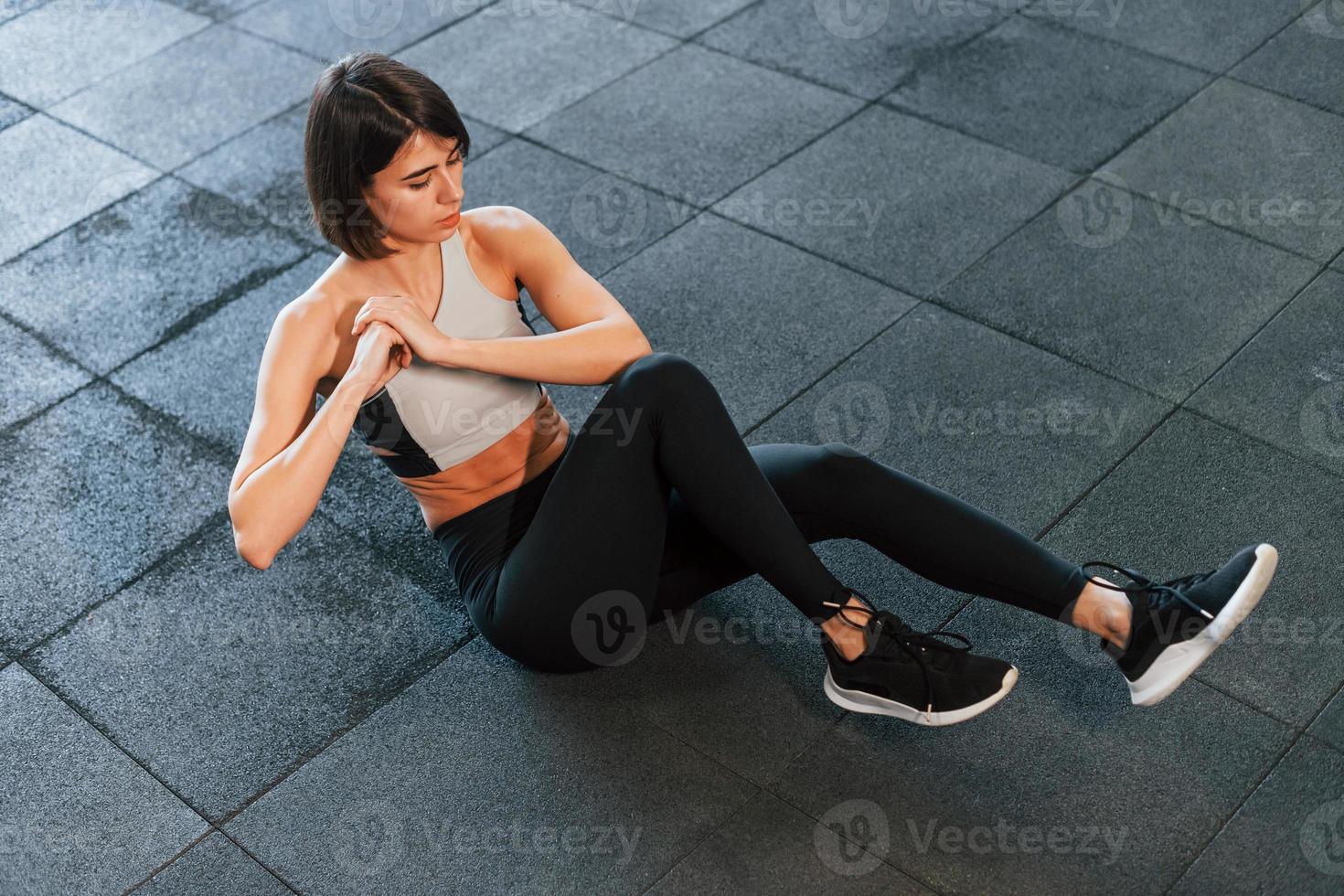Doing abs exercises. Woman in sportive clothes with slim body type is in the gym photo