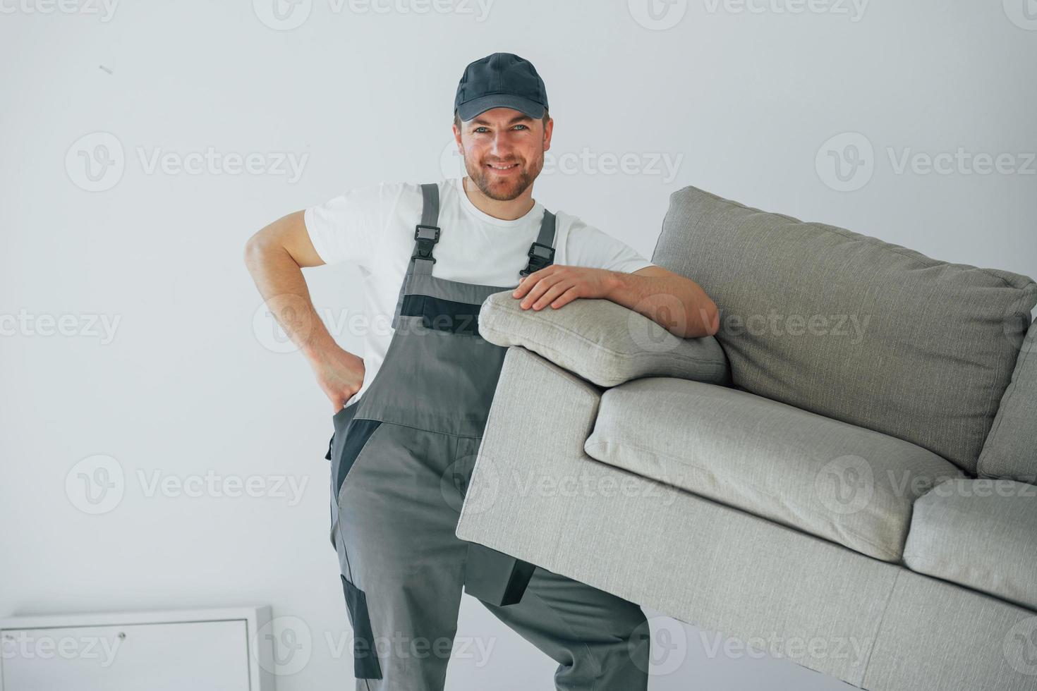 Lifting the sofa. Repairman is working indoors in the modern room photo