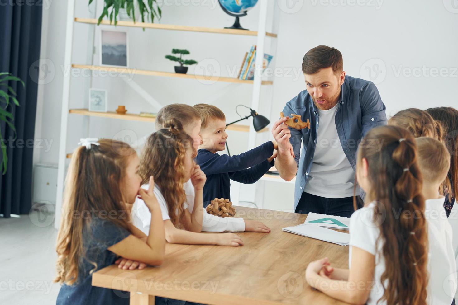 With puzzle. Group of children students in class at school with teacher photo
