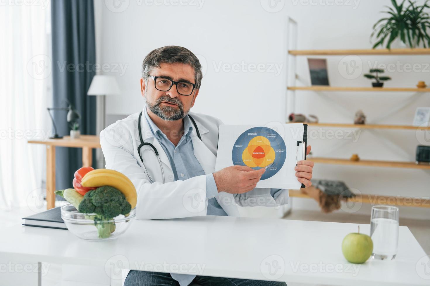 el hombre está mostrando ilustración. concepción de la dieta. trabajador médico profesional con bata blanca está en la oficina foto