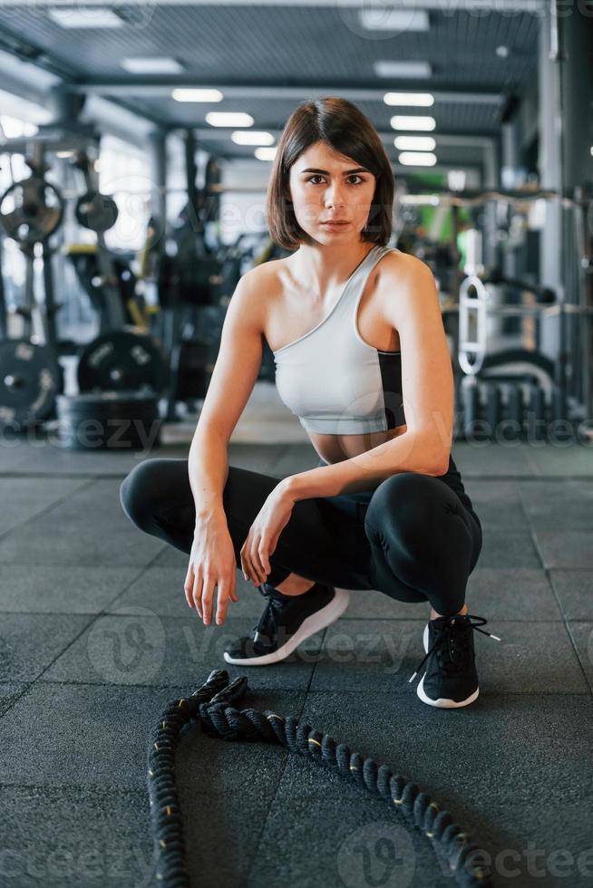 Confident woman in sportive clothes with slim body type is in the gym photo
