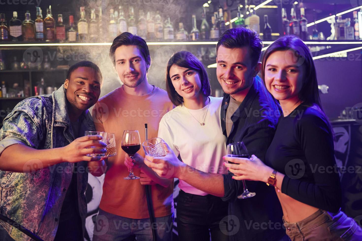 Standing together. Group of friends having fun in the night club photo