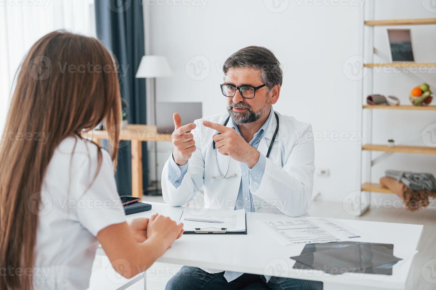 Male doctor giving consultation to the woman. Professional medical worker in white coat is in the office photo