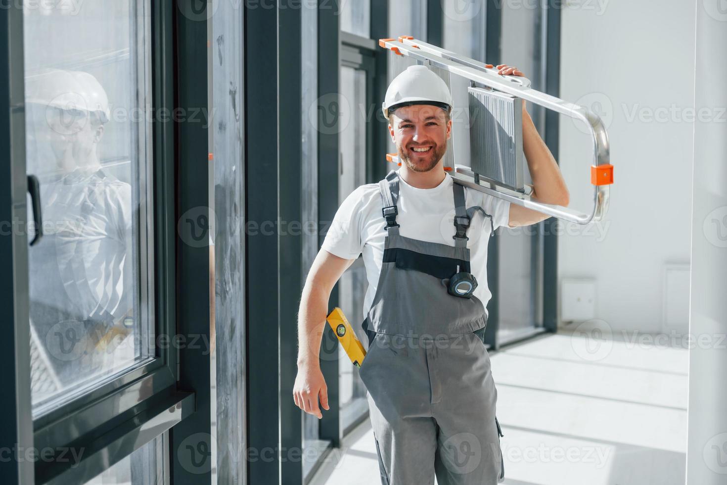 Holding ladder. Repairman is working indoors in the modern room photo
