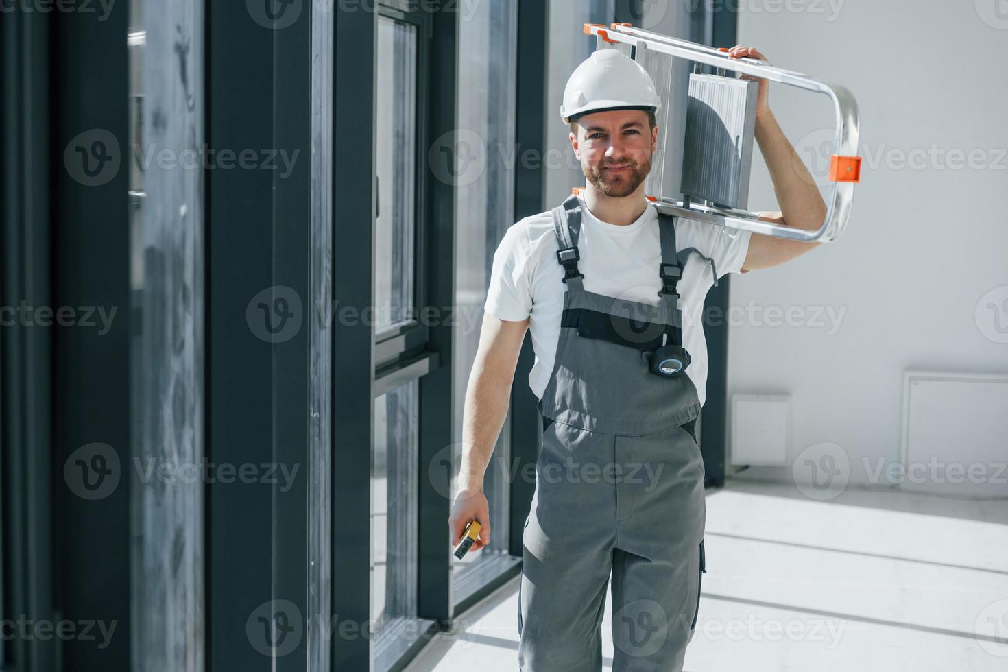Holding ladder. Repairman is working indoors in the modern room photo
