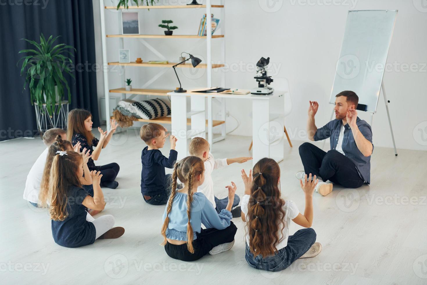 Man teaches gesture language. Group of children students in class at school with teacher photo