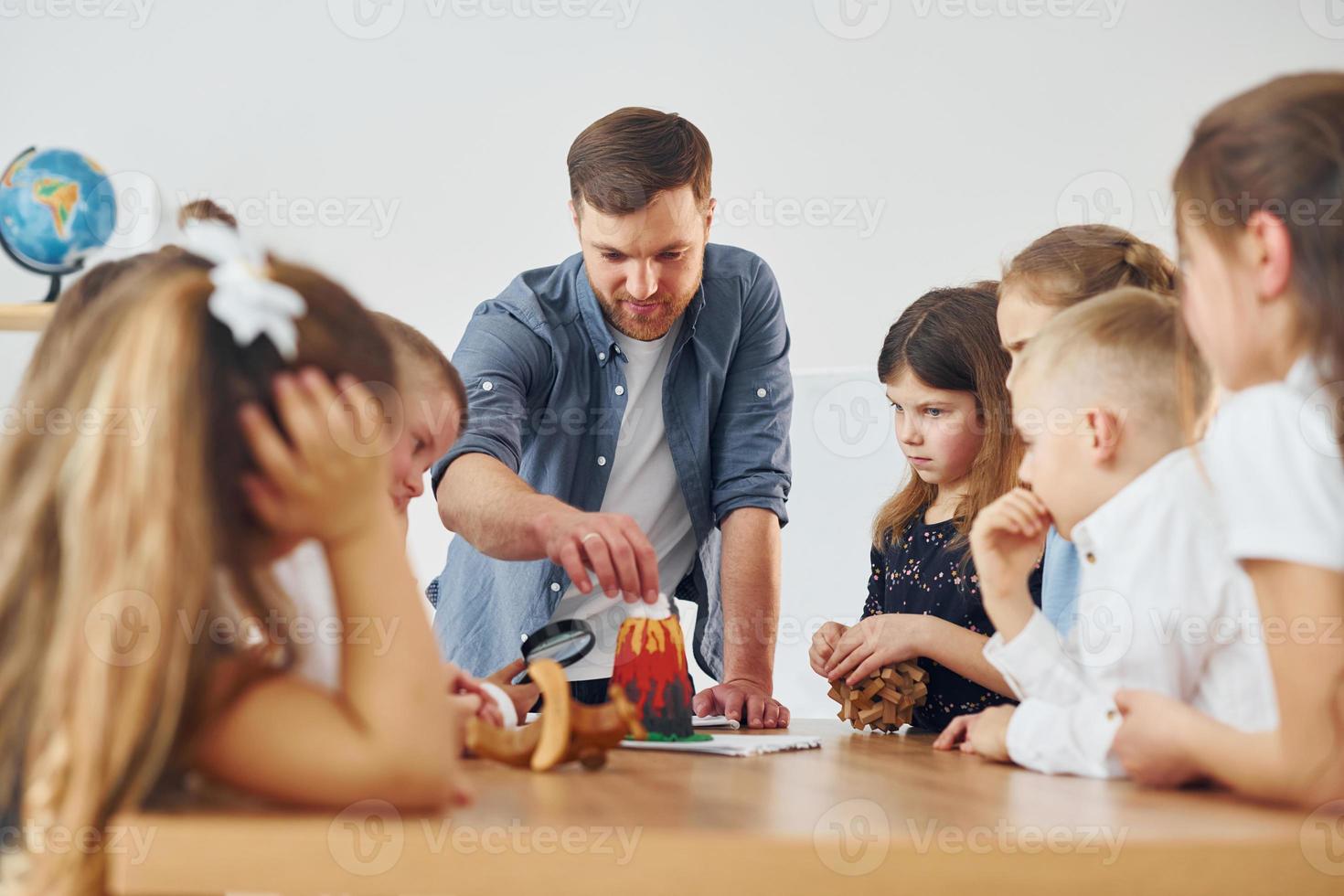 Looking at the little volcano model. Group of children students in class at school with teacher photo