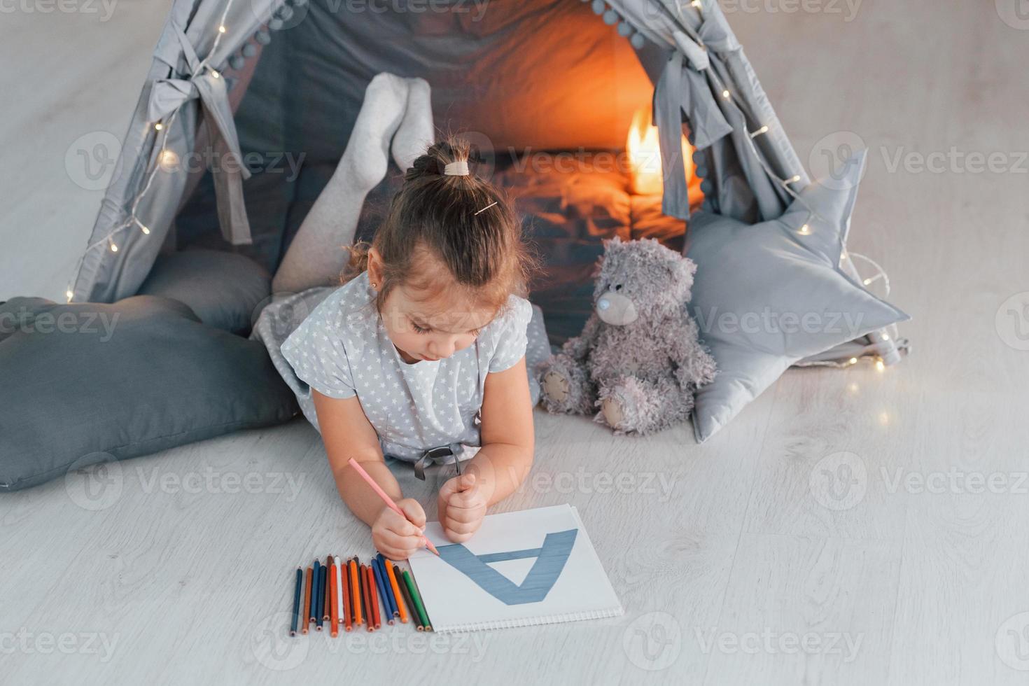 Writing letter. Cute little girl playing in the tent that is in the domestic room photo