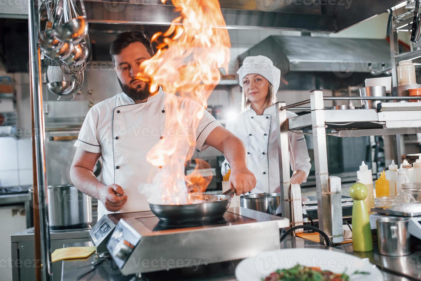 Flames in the frying pan. Professional chef preparing food in the kitchen photo