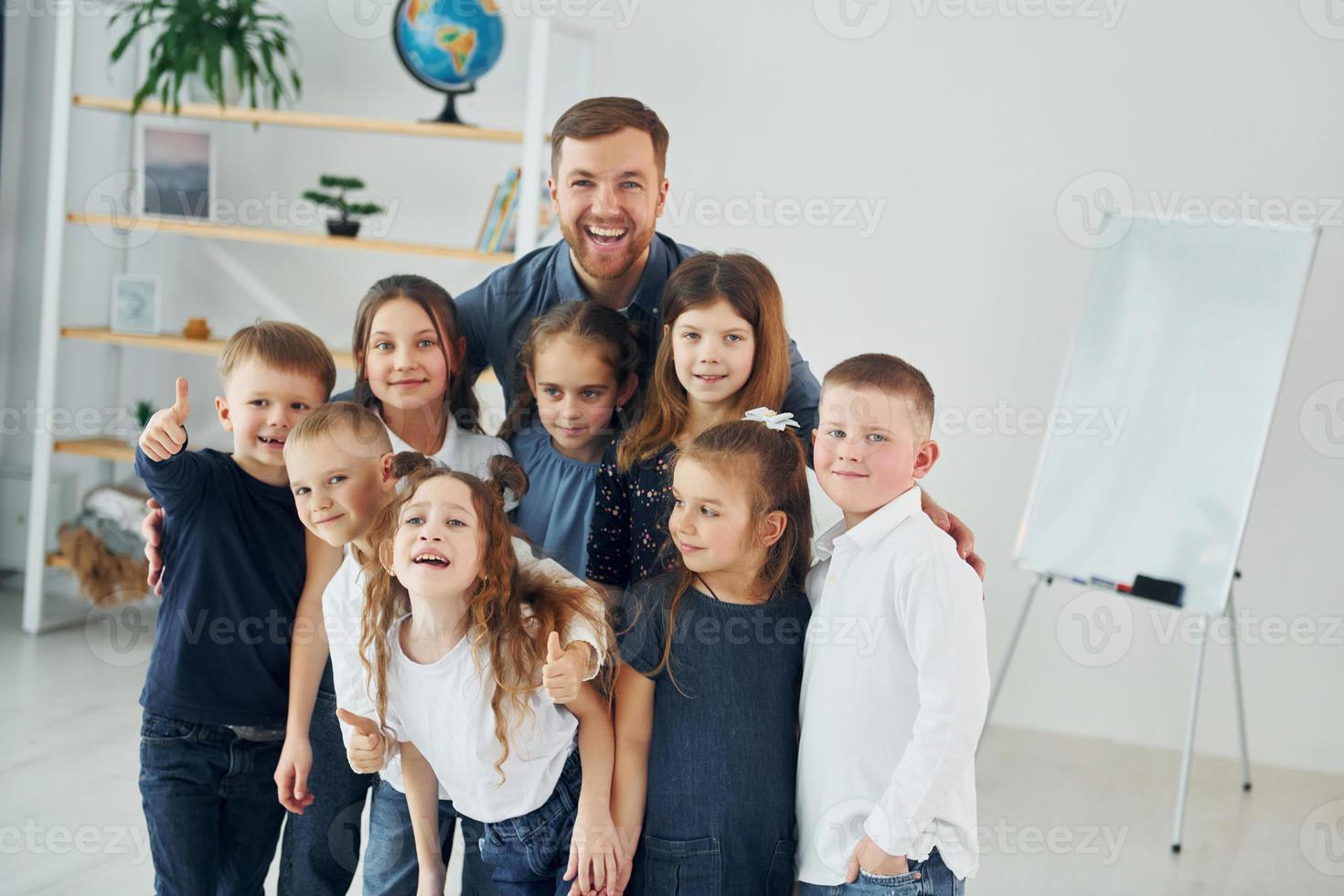 Standing together. Group of children students in class at school with teacher photo