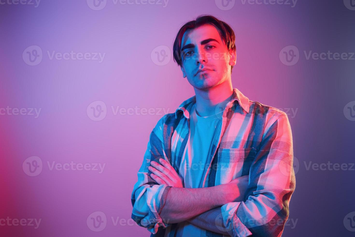 Arms crossed. Man standing in the studio with neon light photo