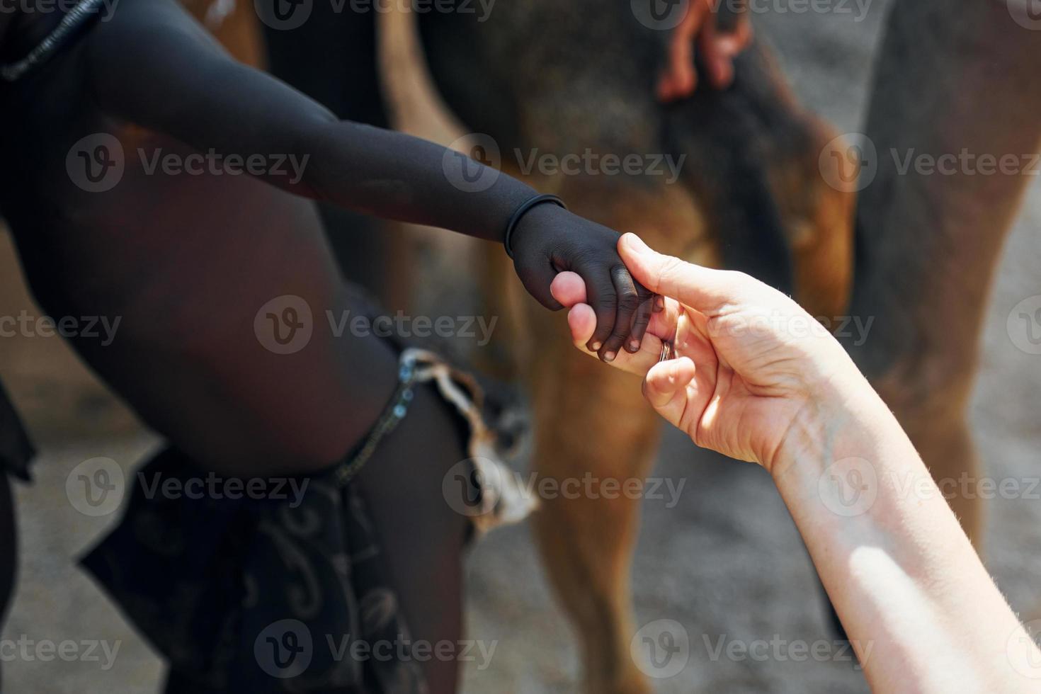 Touching hands, greetings gesture. Tourists is in Namibia with African kids photo