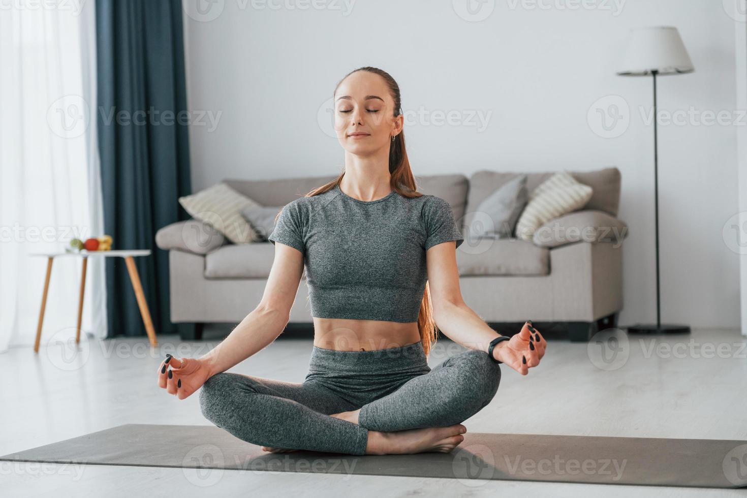 Domestic room. Young woman with slim body type and in yoga clothes is at home photo