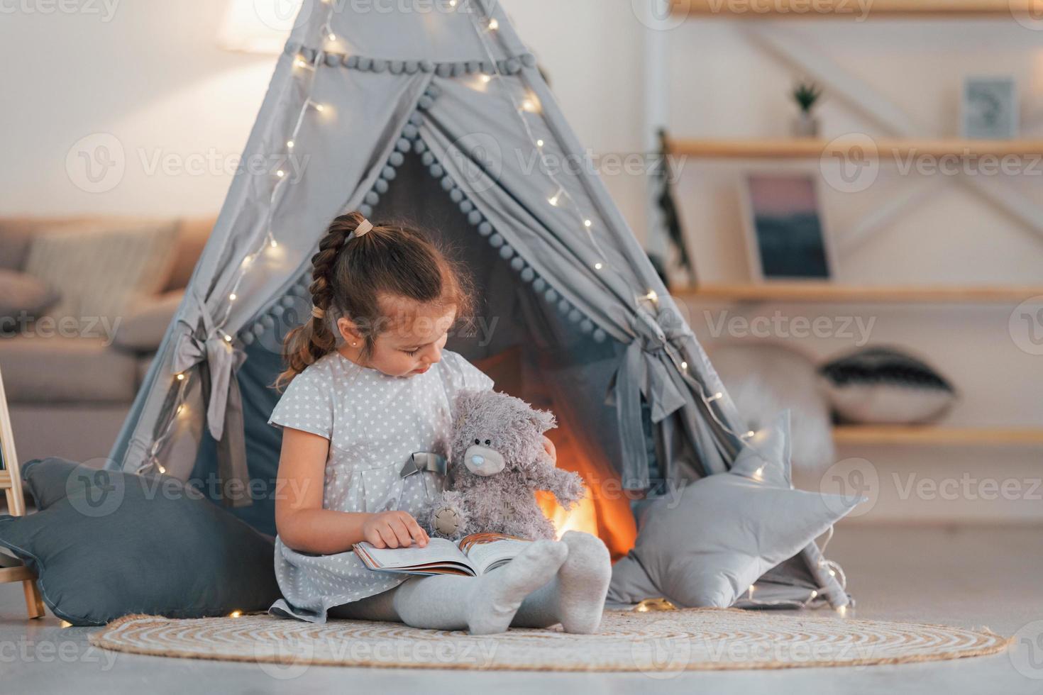 With toy. Cute little girl playing in the tent that is in the domestic room photo