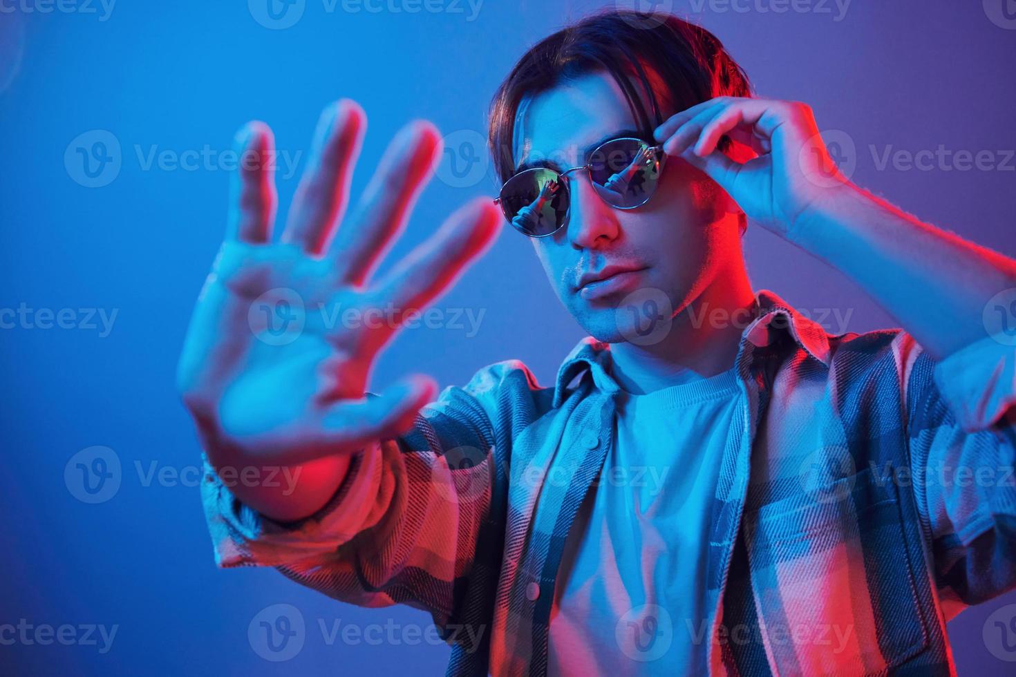 Looking into camera. Man standing in the studio with neon light photo