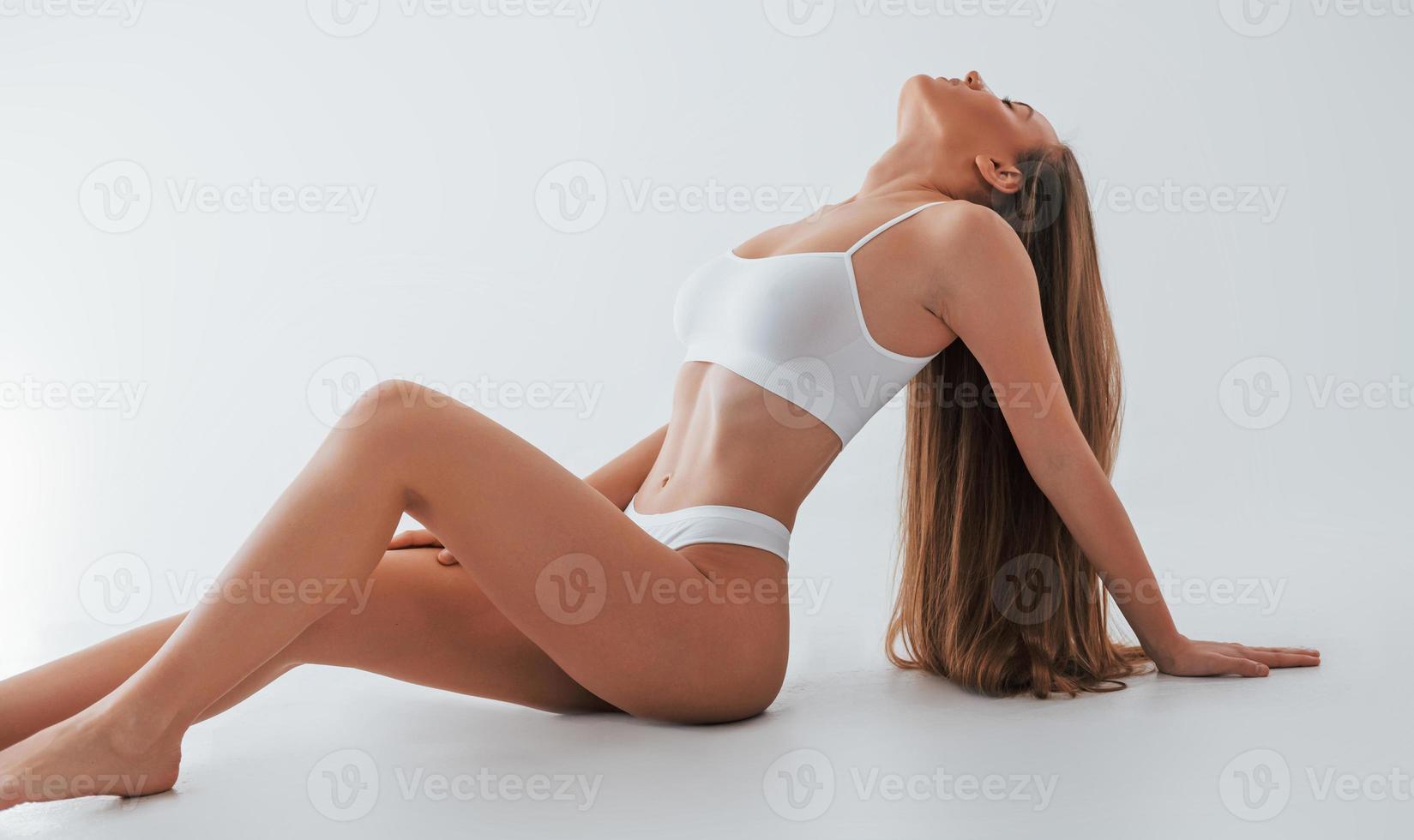 White lingerie. Woman in underwear with slim body type is posing in the studio photo