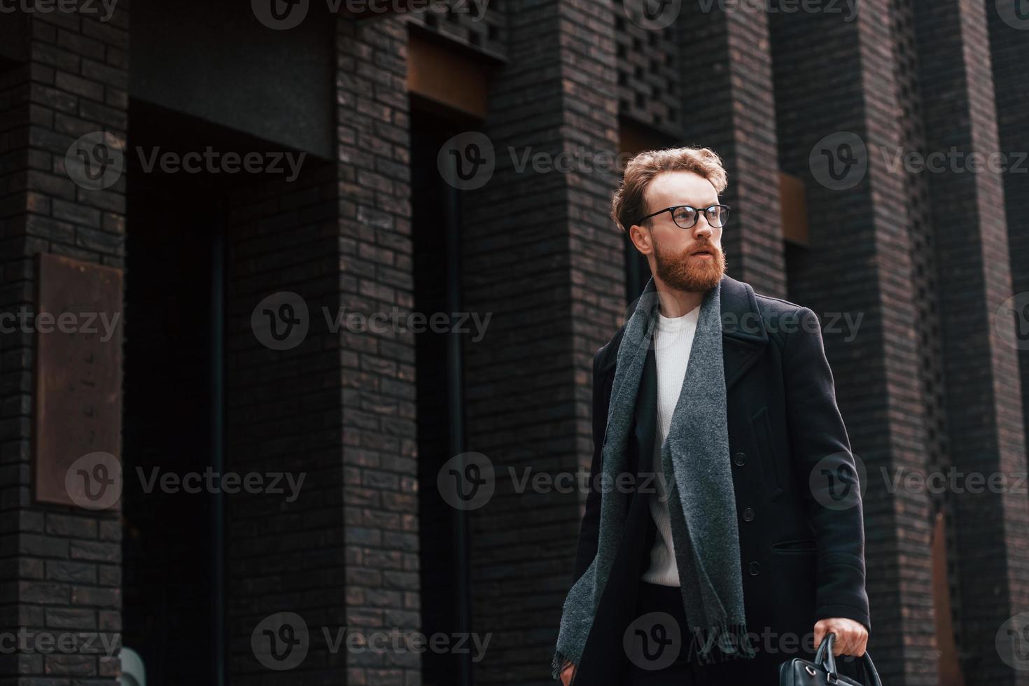 caminando cerca del edificio. hombre elegante con barba y gafas está al aire libre foto