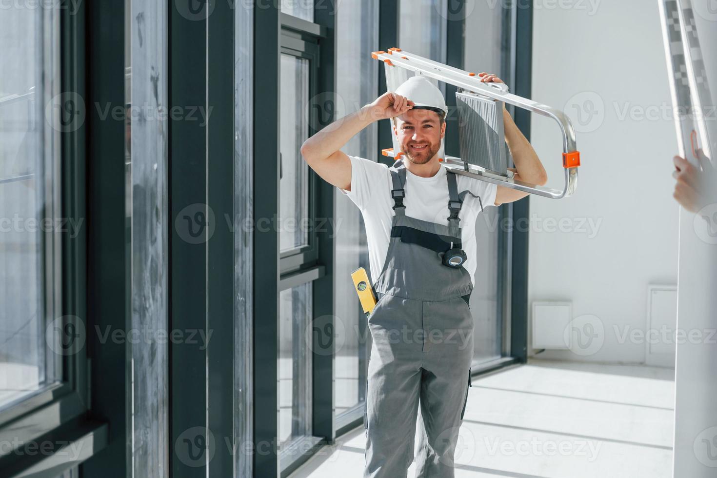 Holding ladder. Repairman is working indoors in the modern room photo