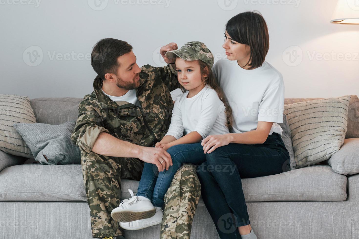 On the sofa. Soldier in uniform is at home with his wife and daughter photo