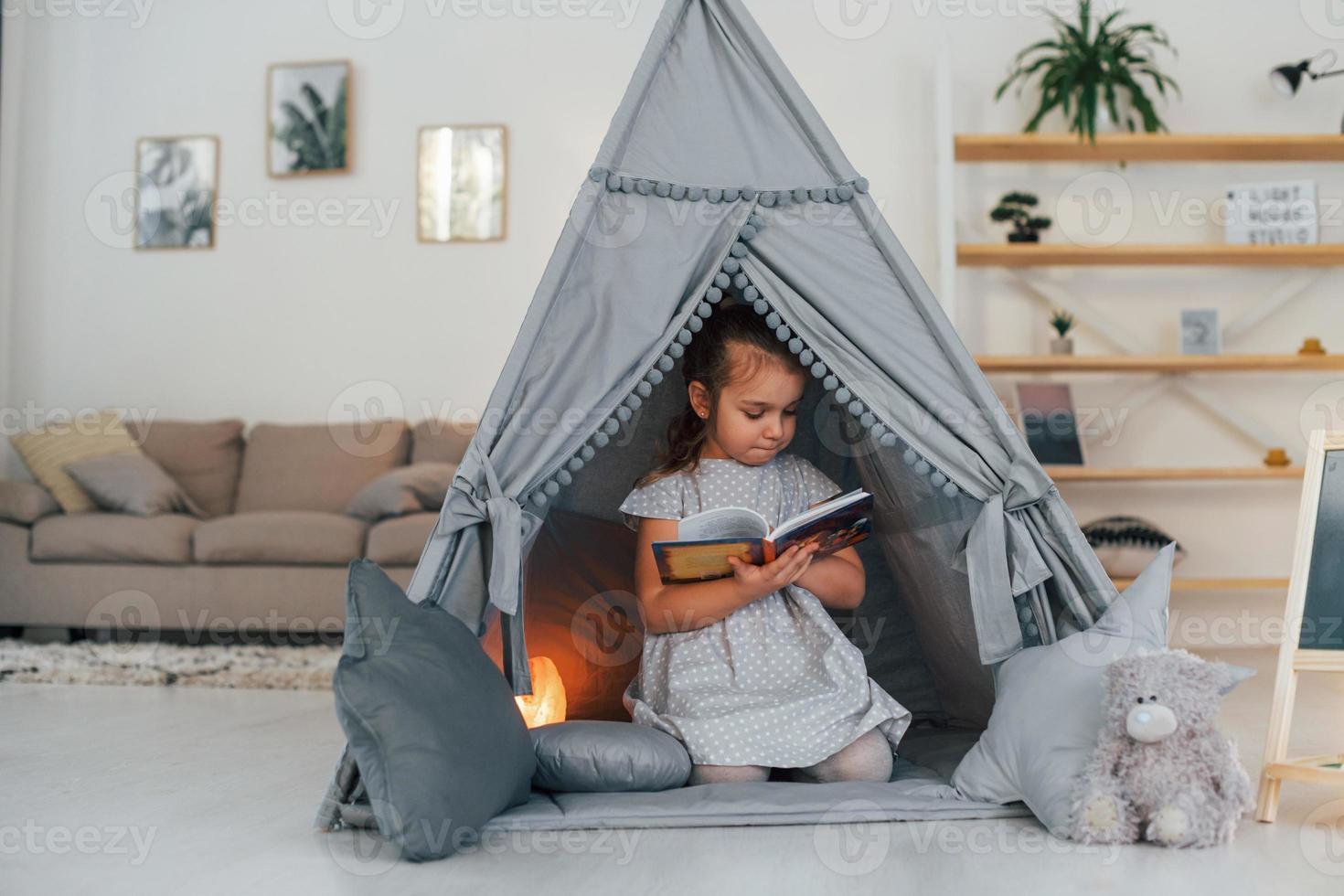 Cute little girl playing in the tent that is in the domestic room photo