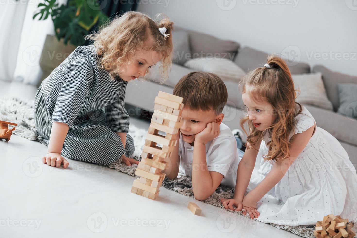 Playing wooden tower game. Group of children is together at home at daytime photo