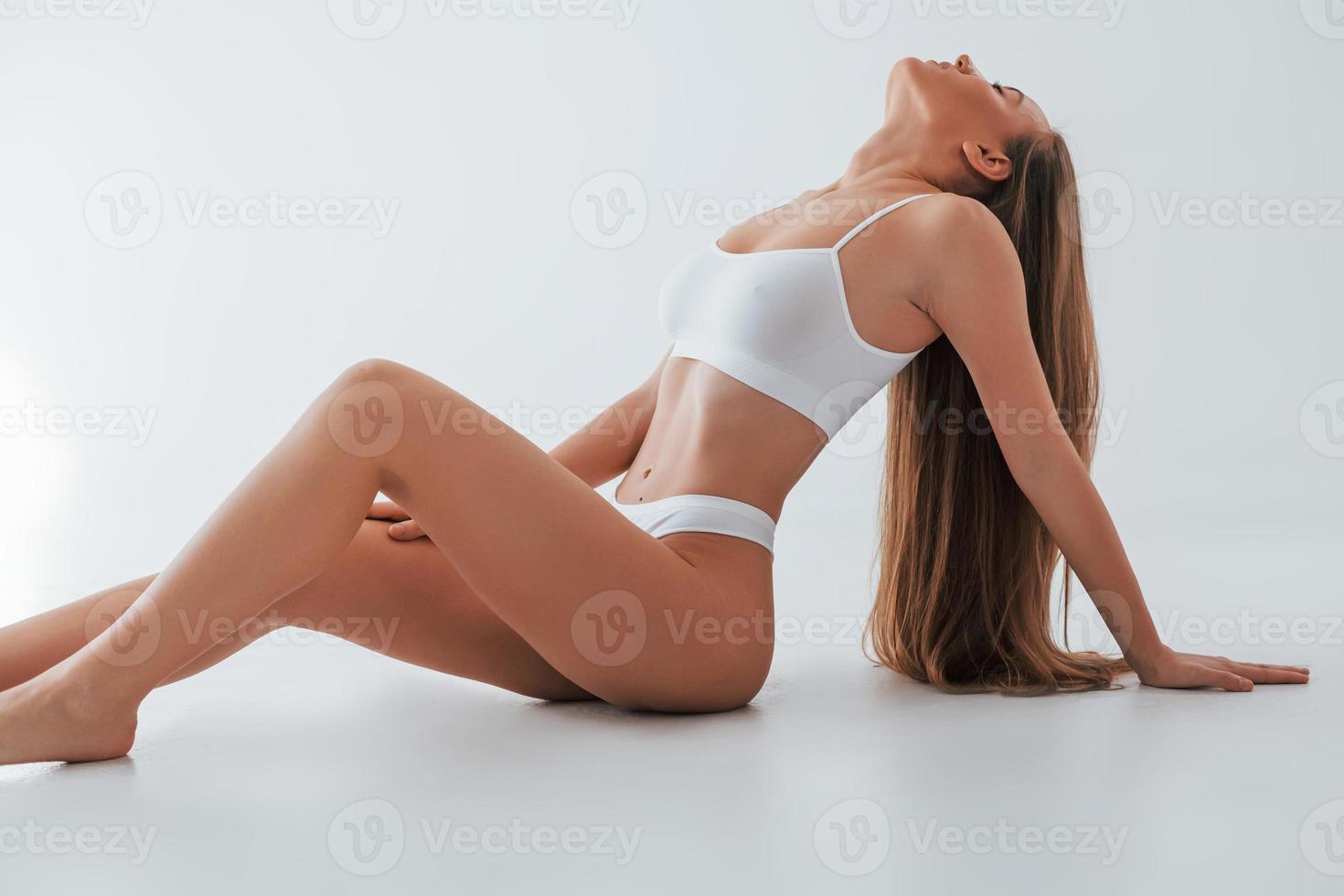 White lingerie. Woman in underwear with slim body type is posing in the studio photo