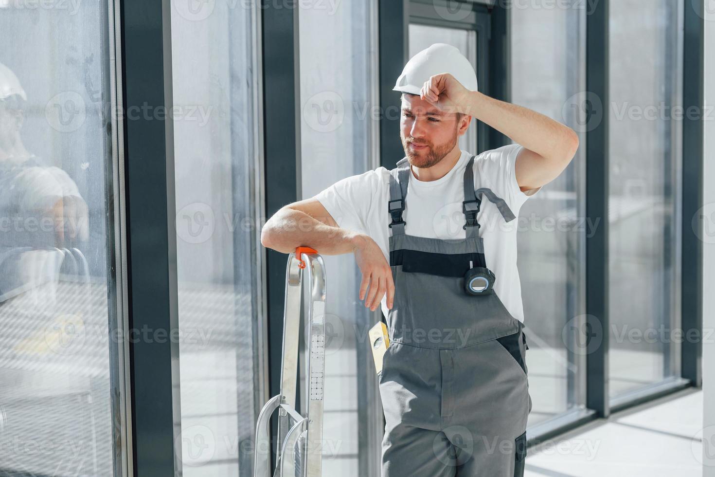Holding ladder. Repairman is working indoors in the modern room photo