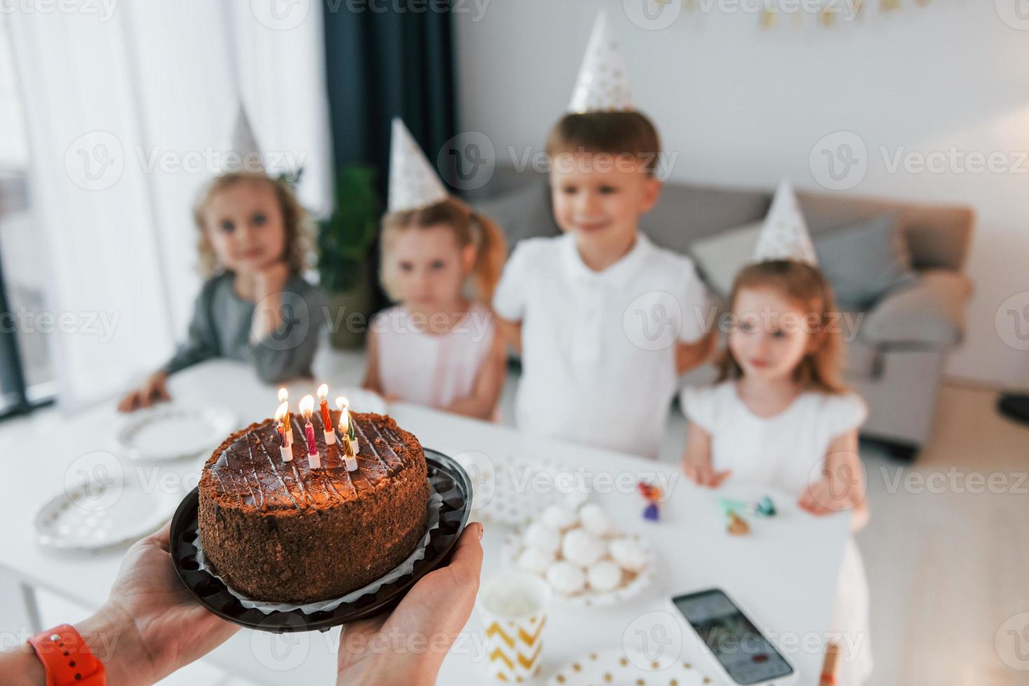 mujer sosteniendo pastel con velas. celebrando cumpleaños. grupo de niños  está juntos en casa durante el día 8366630 Foto de stock en Vecteezy