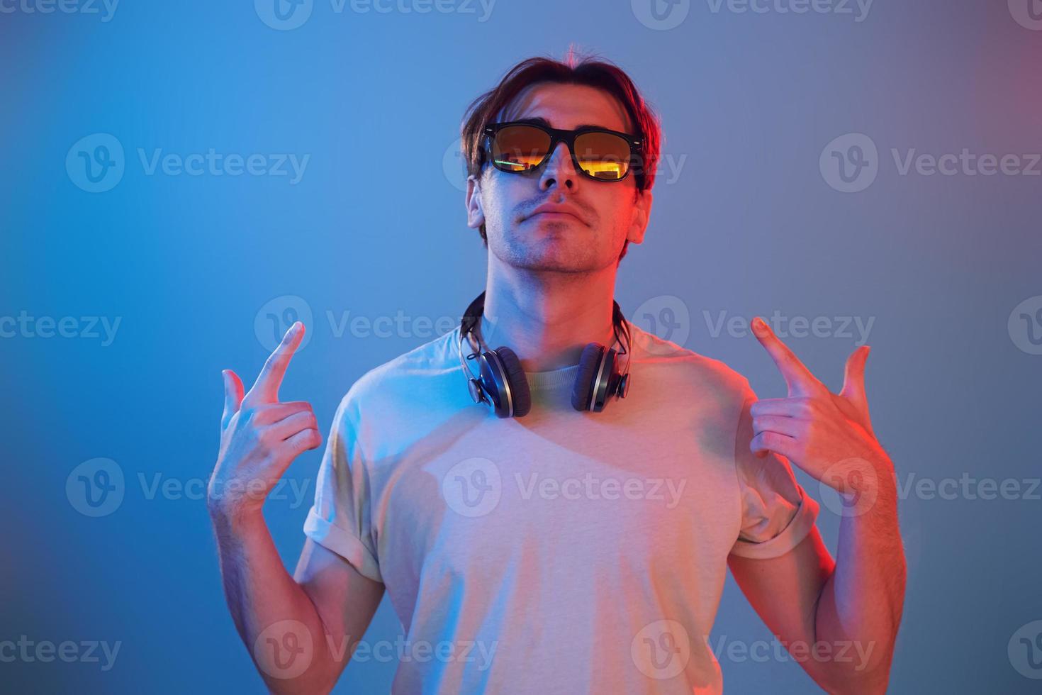 Showing gestures. Man standing in the studio with neon light photo