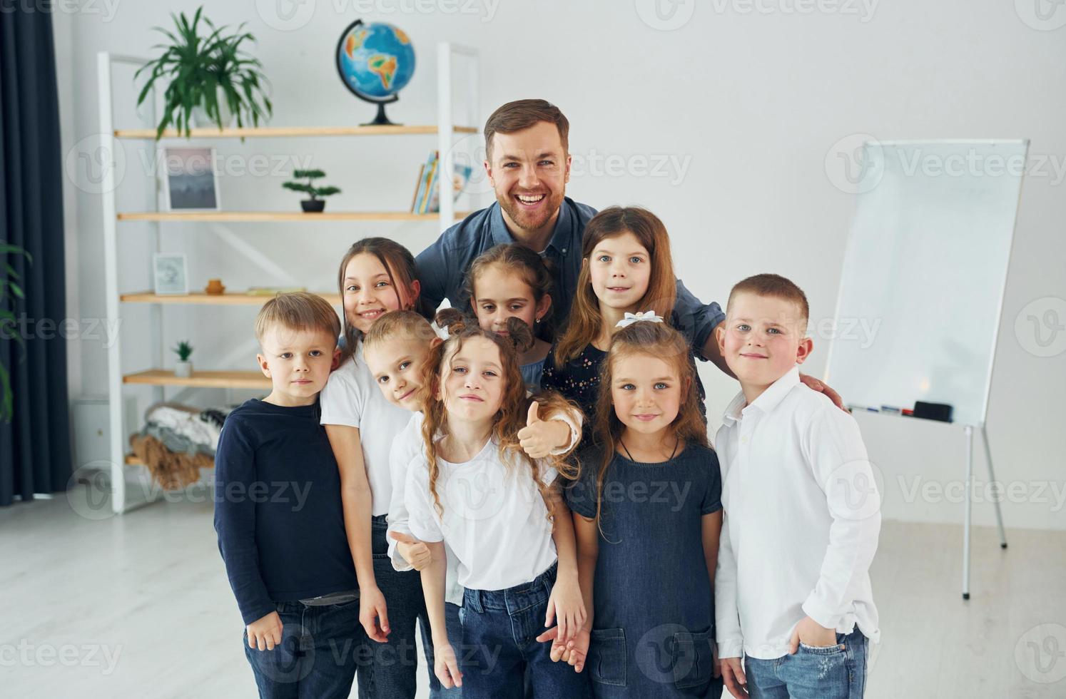 Standing together. Group of children students in class at school with teacher photo