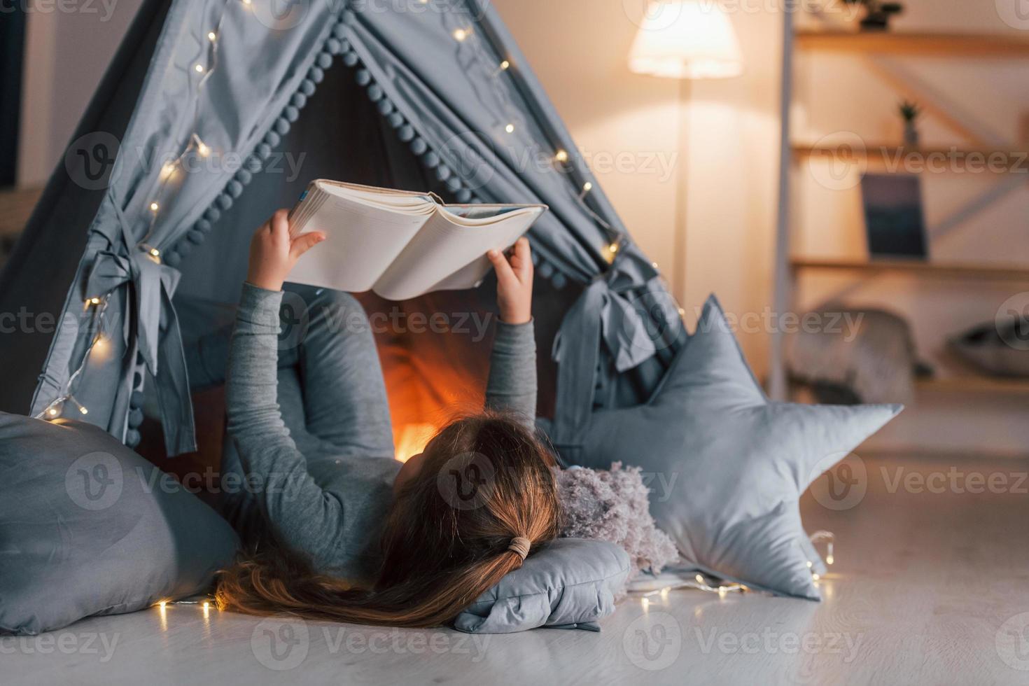 Interesting book. Cute little girl playing in the tent that is in the domestic room photo
