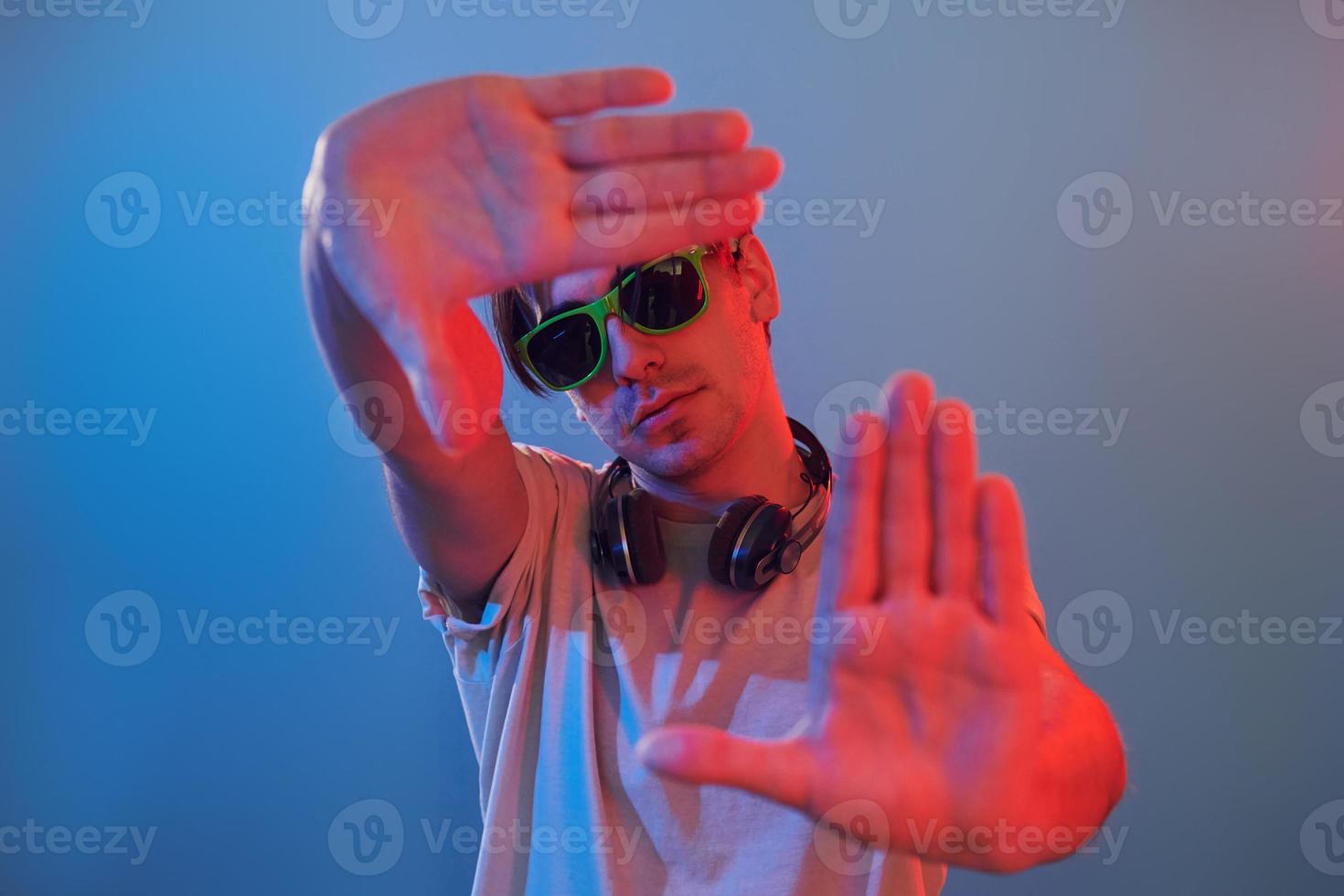 Showing gestures. Man standing in the studio with neon light photo