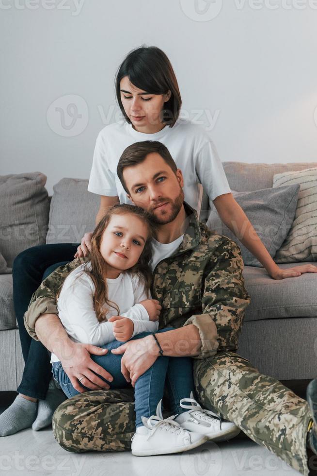 Embracing each other. Soldier in uniform is at home with his wife and daughter photo